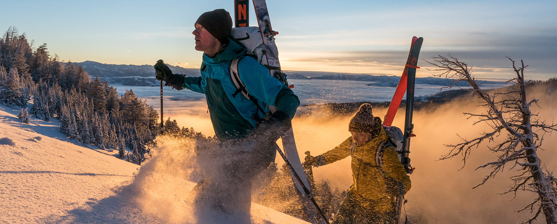 Two skiers hiking their way up in the backcountry at sunrise.