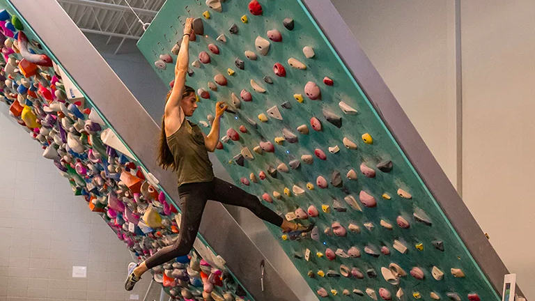 MHW Athlete Kyra Condie trains on a boulder wall in the gym