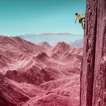 Infrared image of a climber looking up for her next move, close to the top of a route.
