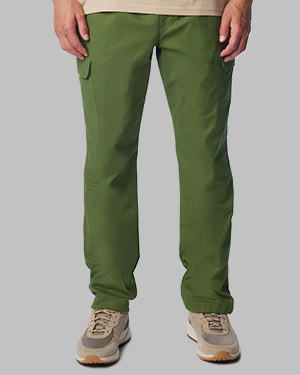 A man from the waist down in roomy green pants and sneakers.