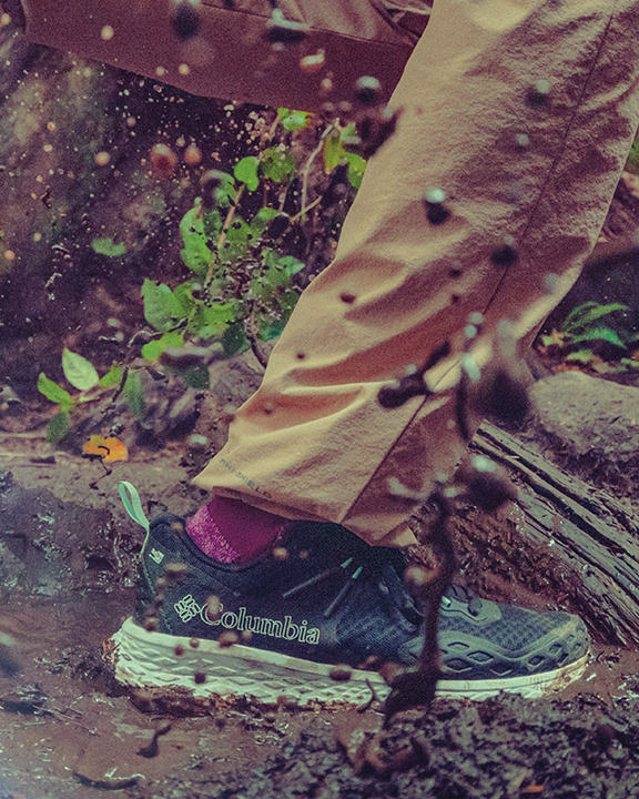 Close-up of a hiker trekking on a muddy trail in Omni-MAX shoes. 