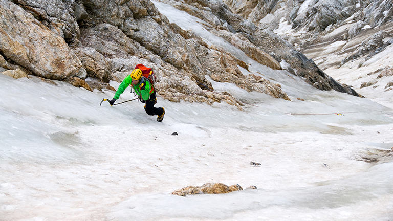 Image of an ice climber, head down, in the middle of a route.