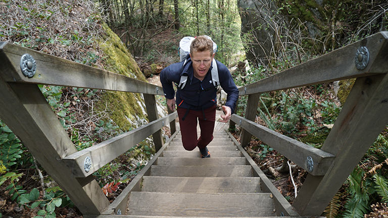 Mountain Hardwear Tim Emmett trains outside on a flight of stairs with backpack on.