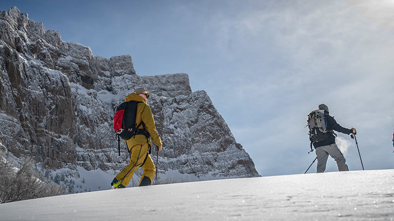 Two alpinists walking in a snowy mountain landscape on a sunny bluebird day.