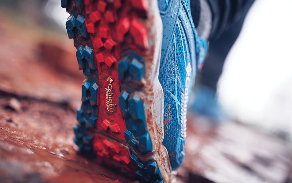 Closeup of a Columbia shoe outsole on a muddy trail.