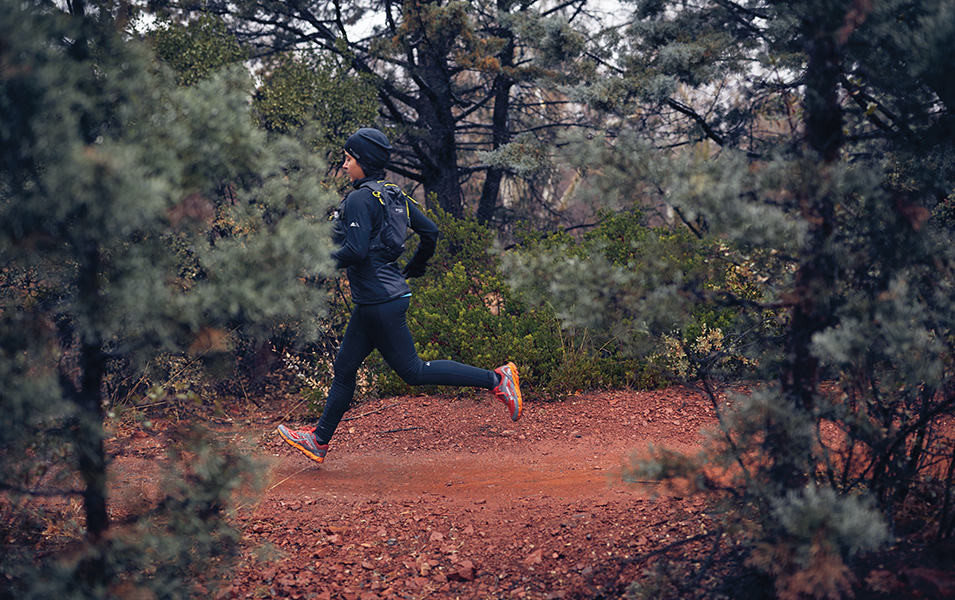 Woman running on a dirt trail in the woods.