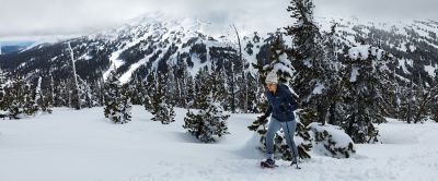 Woman snowshoeing in a winter mountain scene.