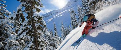 A skier comes down an untracked powder run on a beautiful bluebird day.  
