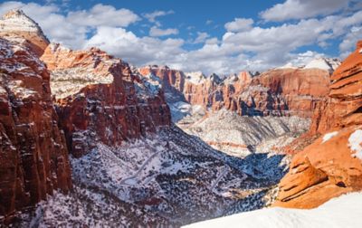 Snow speckles beautiful rust-colored rocks that tower in the distance in Zion National Park.