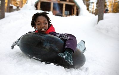 A boy tubing down a snowy hill. 