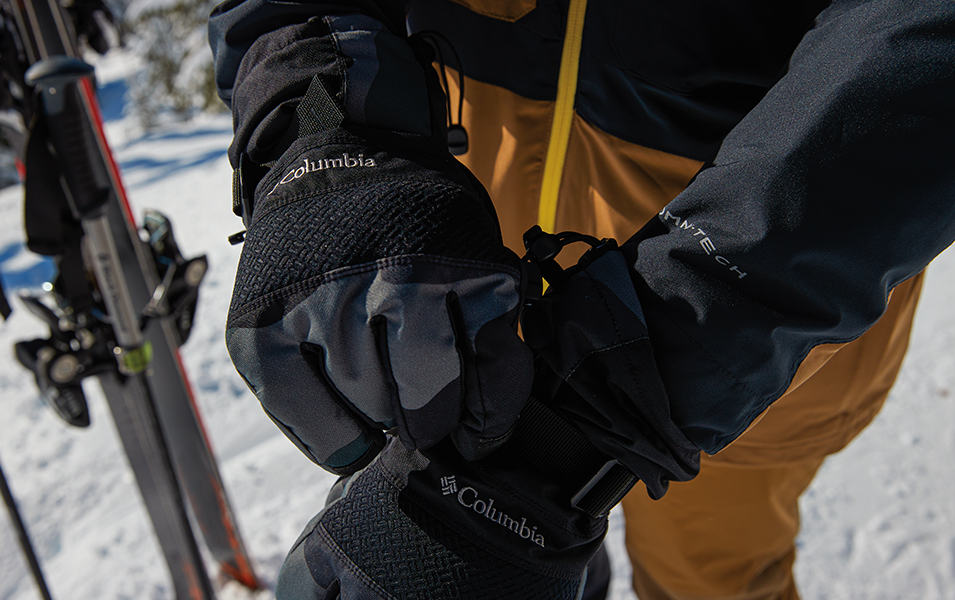 A skier adjusts his winter gloves on the mountain. 