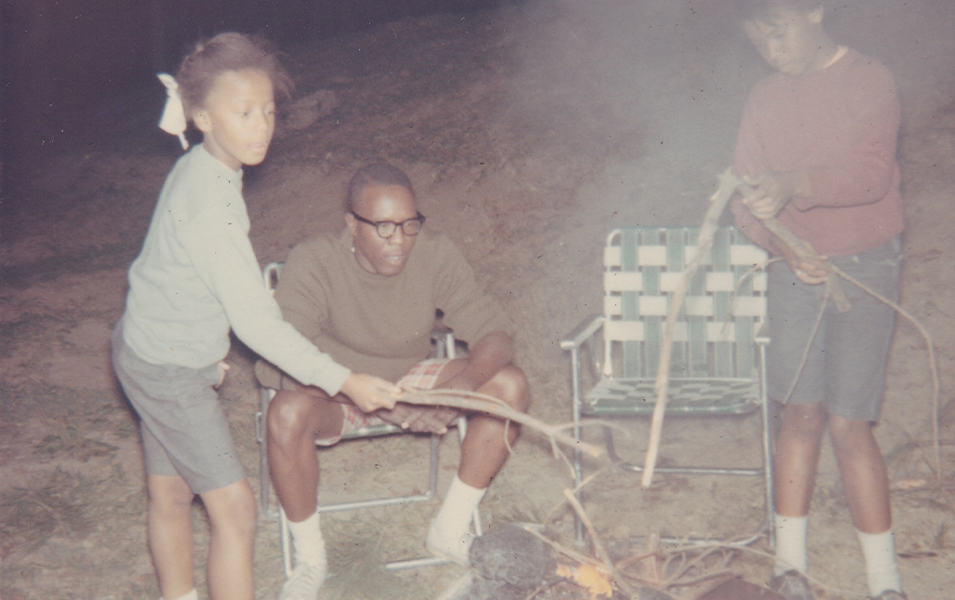 An old snapshot timestamped “Dec 1967” shows Benjamin Graham sitting around a campfire with his granddaughters. 