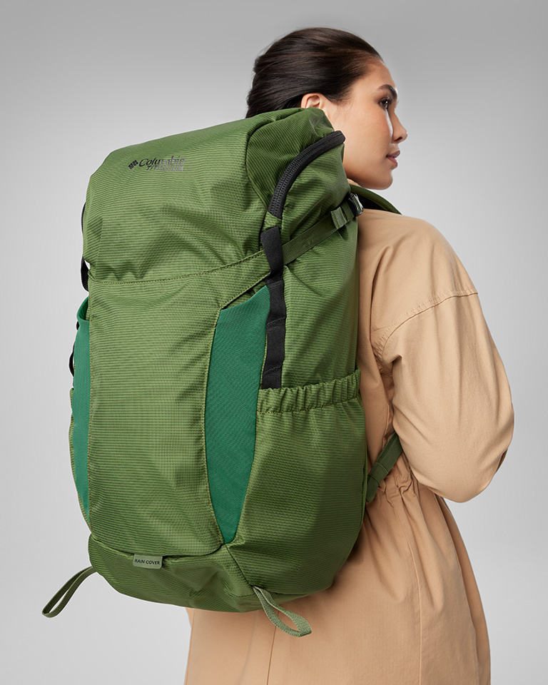 A woman with a big green backpacking pack on and a tan jacket.