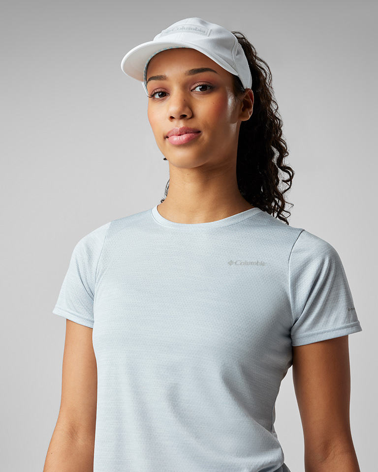 A woman in a pony-tail ball cap and matching light blue performance tee.