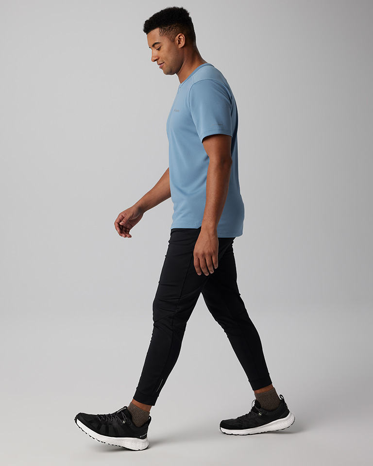 A man in a blue shirt, a black pants, and black sneakers.