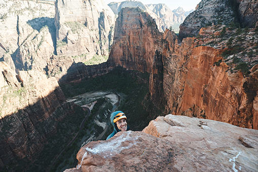Nearing the top of a route in Zion National Park, Ethan smiles at the camera
