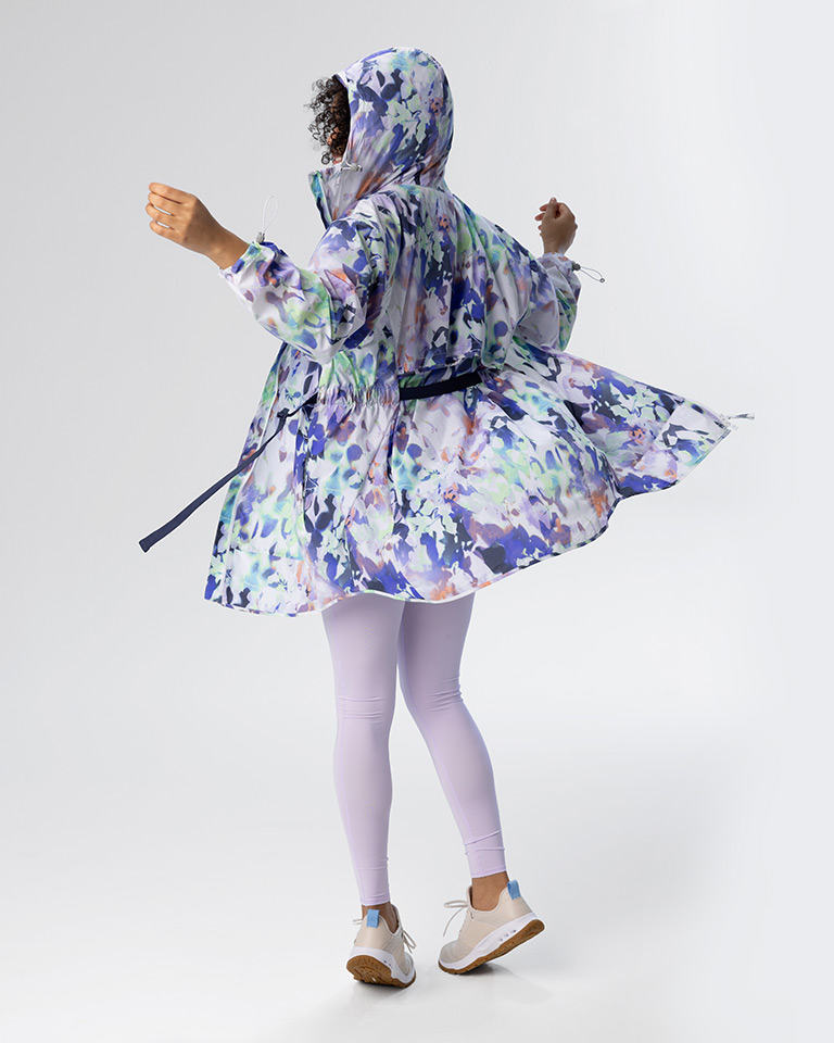 Outfit 3, a floral inspired lightweight UPF 50 protection with a matching tank and leggings with tan sneakers. The model is twirling to show the flare of the jacket.