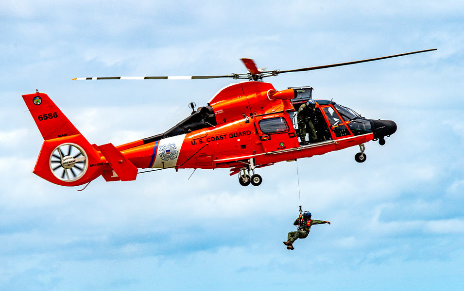 A U.S. Coast Guard photo showing a rescue swimmer being hoisted out of a helicopter. 