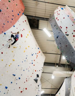 Kyra Condie bouldering in her home climbing gym in Minneapolis, making good progress on the route, with her personal mantra, "you suck try harder" on the wall in the background.