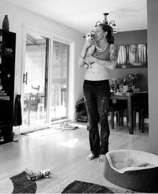 Black and white image of Alex Johnson, at home, holding her dog.