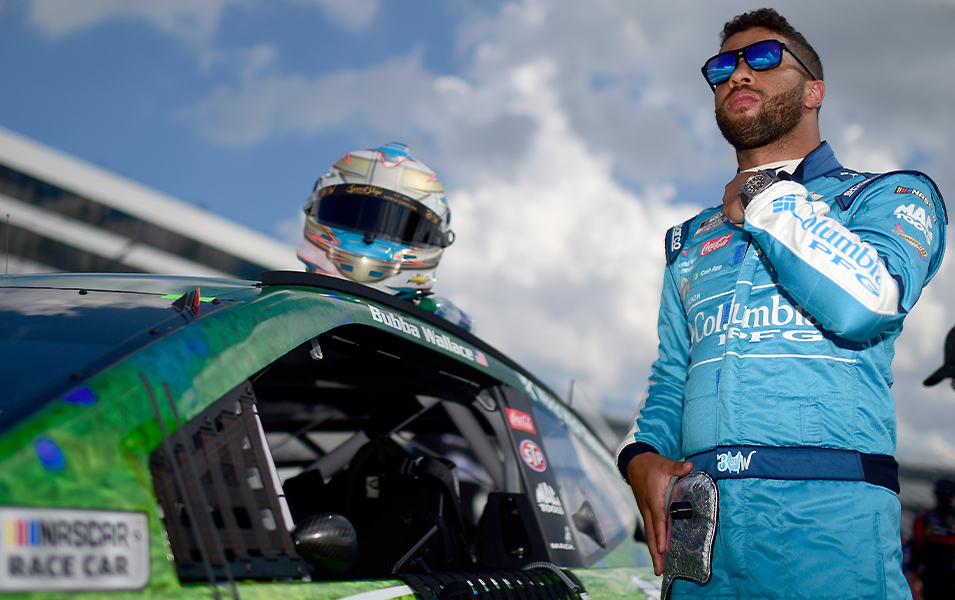 Bubba Wallace getting ready for a Nascar race standing next to his car.
