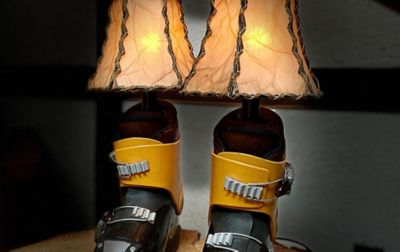  Two cute lamps made out of old ski boots sit on a small table in a dark room, emitting a soft glow. 