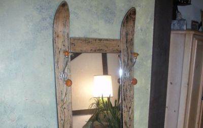 A mirror sits on a wall made with old skis as the frame. 