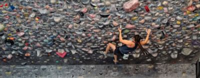 Kyra Condie climbing on a bouldering problem in a climbing gym.
