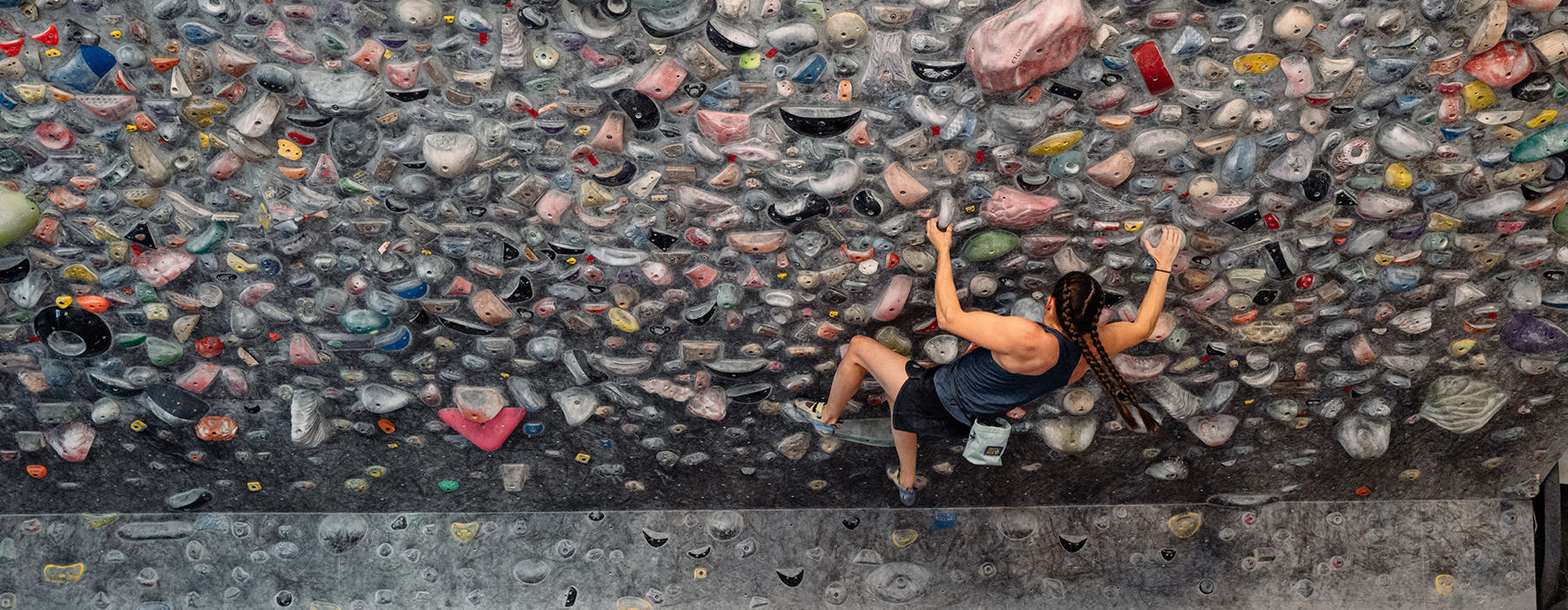 Kyra Condie climbing on a bouldering problem in a climbing gym.
