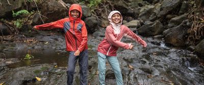 Two kids dancing in the rain in a rocky cove. 