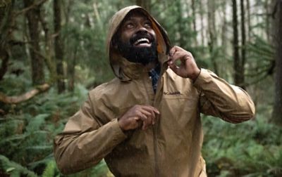 Homme dans une forêt pluvieuse portant une veste de pluie marron clair Columbia Sportswear.