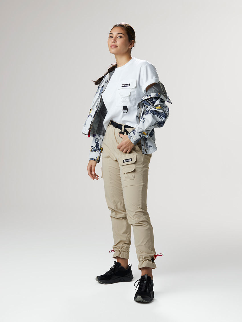 Carry On outfit: boxy white tee with utility pockets and buckles, a boxy windbreaker with lots of pockets and a floral print, and khaki fitted cargo pants with sneakers.