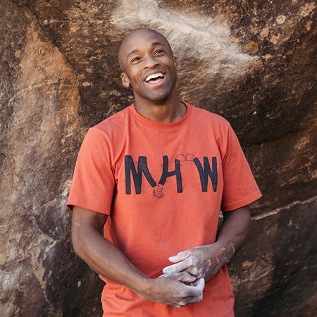 Boulderer Ayo smiles with his hands chalked in between climbing 