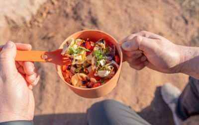 A plastic camping fork digs into a bowl of pasta salad.