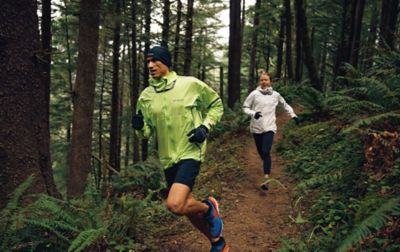 Man and a woman running on a forest trail. 