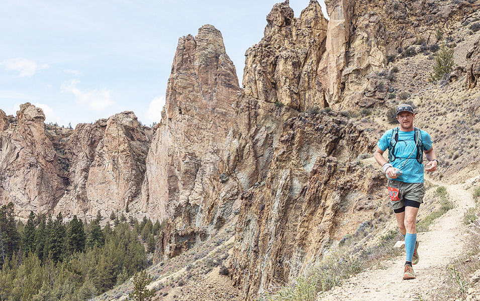 Professional trail runner Willie McBride runs down a trail in a scenic high desert setting.  

 