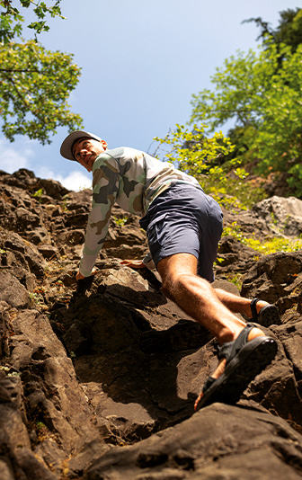 Man in Columbia gear climbing up a rocky wall.