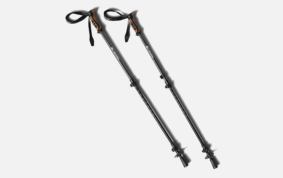 A product image of a pair of black Columbia Sportswear trekking poles with light brown handles set against a white background. 
