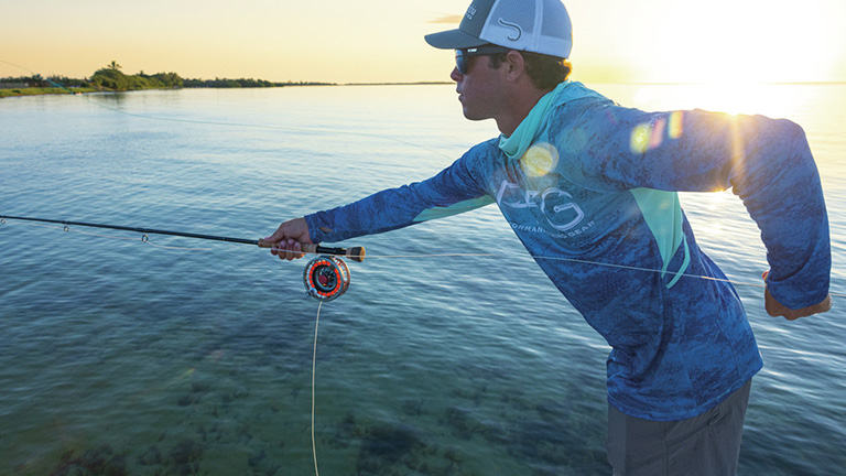 Photo of a man casting a fly fishing rod with bright sun in the background.