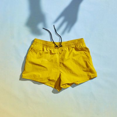 Laydown of the Stryder shorts on a gradient background with shadow hands lingering over the shorts.