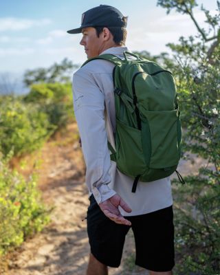 A younger man with a backpack on a trail.