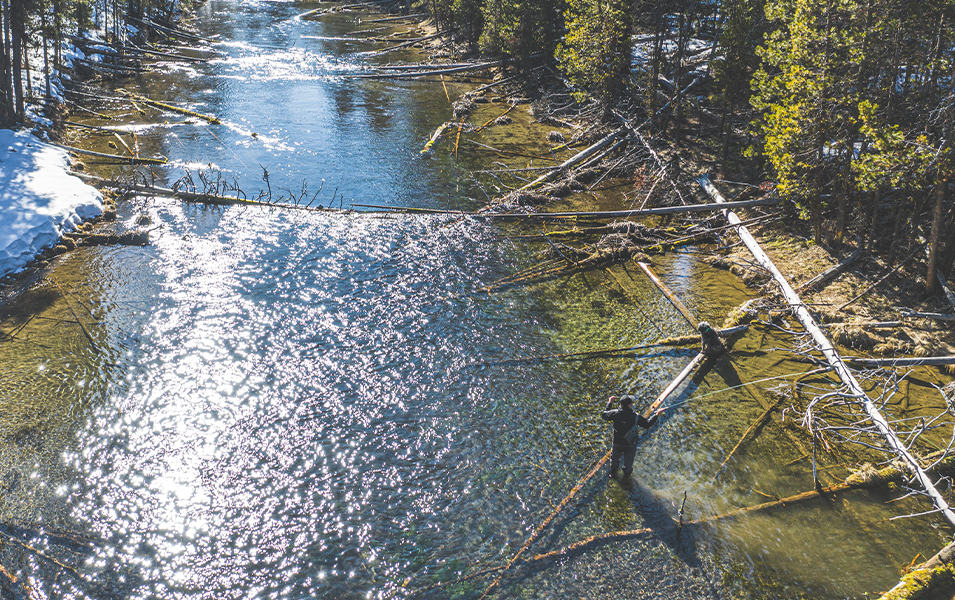 An aerial photo of a man in a river fly fishing from a distance. 