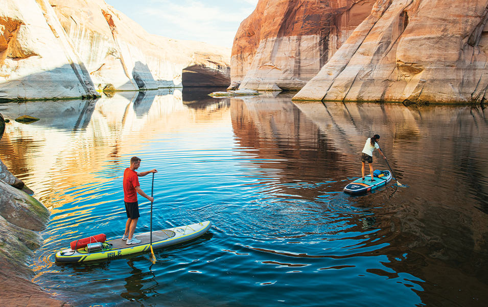 Two people paddle boarding on a lake.