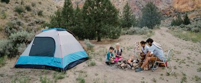 Family sitting around a fire at campsite. 