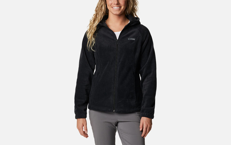 A product shot of a woman wearing a black Columbia Sportswear Benton Springs full zip hoodie with a gray background.