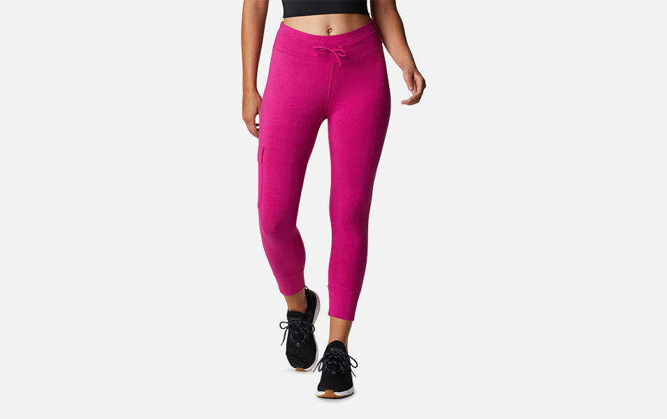 A product shot of a woman wearing bright pink Columbia Sportswear Columbia Trek capri leggings with a gray background.