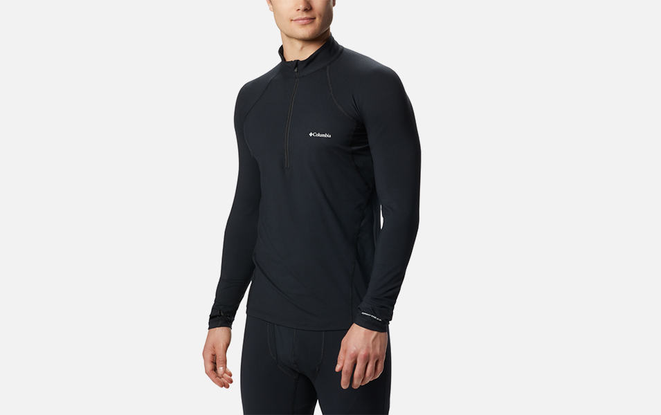 A product shot of a man wearing a black Columbia Sportswear midweight stretch half zip baselayer top with a gray background.