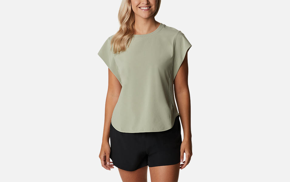 A product shot of a woman wearing a khaki-colored Columbia Sportswear Bowen Lookout short sleeve top with a gray background.