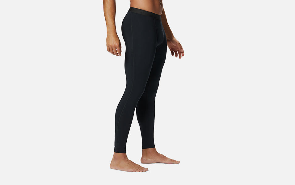 A product shot of a man wearing black Columbia Sportswear midweight stretch baselayer tights with a gray background.