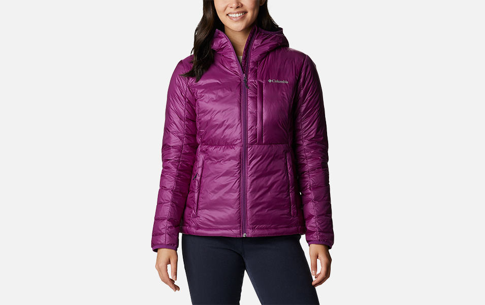 A product shot of a woman wearing a purple Columbia Sportswear Infinity Summit Omni-Heat Infinity down hooded jacket with a gray background.